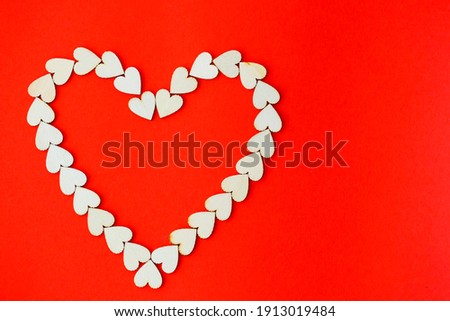 Heart lined with wooden hearts on a bright red background. Place for an inscription, romantic picture for Valentine's Day