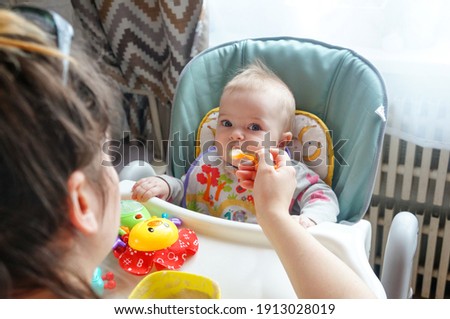 mom feeds the baby with a spoon of porridge, mom gives food to her eight-month-old baby at home. Baby food.