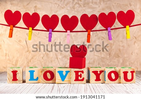 A declaration of love. Cubes with the inscription I love you. A box with a heart. The background is on February 14. A garland of 7 red hearts. Valentines day greeting card.