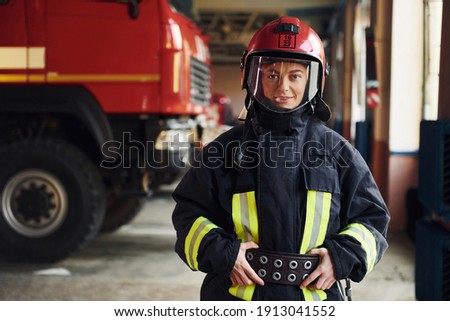 Female firefighter in protective uniform standing near truck.