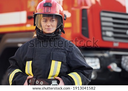 Female firefighter in protective uniform standing near truck.