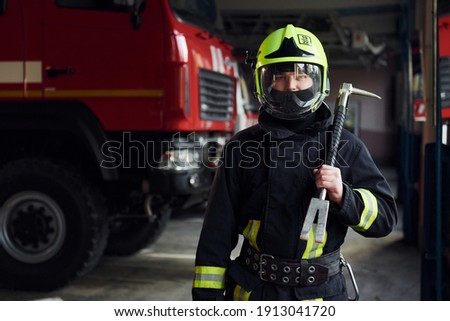 Male firefighter in protective uniform standing near truck.