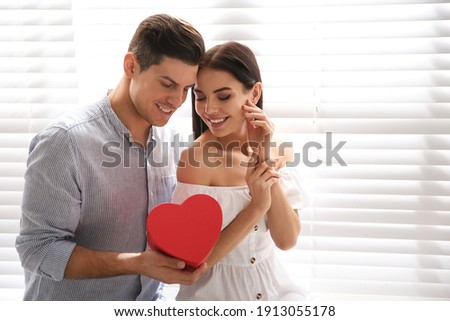 Lovely couple with gift box at home. Valentine's day celebration Royalty-Free Stock Photo #1913055178