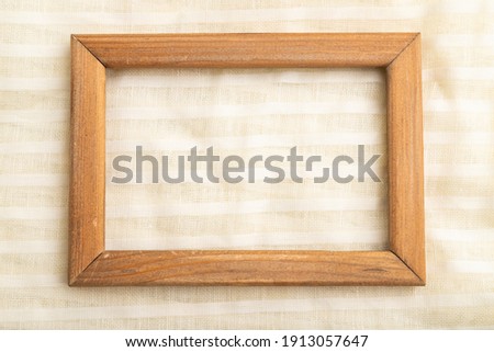 Wooden frame on smooth white linen tissue. Top view, flat lay, natural textile background and texture.
