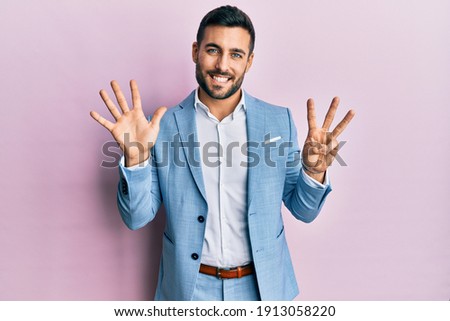 Young hispanic businessman wearing business jacket showing and pointing up with fingers number eight while smiling confident and happy. 
