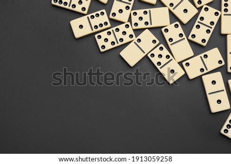 Classic domino tiles on black background, flat lay. Space for text