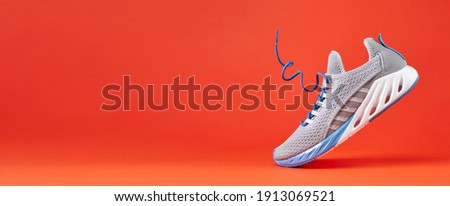 Fashion stylish sneakers with flying laces. Running sports shoes on orange background. Close up. Royalty-Free Stock Photo #1913069521