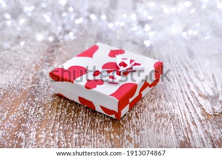 Background holiday, gift in a beautiful box with hearts on wooden table