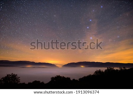 Starry sky above a foggy landscape in a cold autumn night