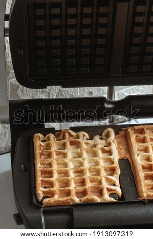 gripping waffles in a waffle iron. Belgian wali in preparation. view from above. close-up. place for the recipe.