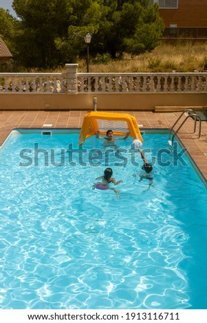 Three kids playing with a ball on a pool