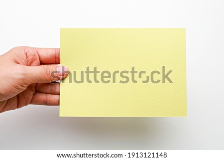 Female hand holds blank color card on a white background.