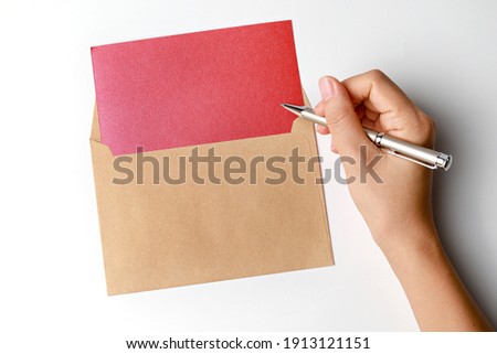 Woman’s hands writing with pen over blank paper card isolated on white background. Top view