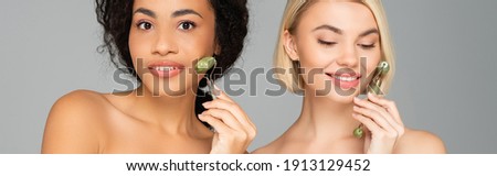 Young multicultural women using jade rollers isolated on grey, banner