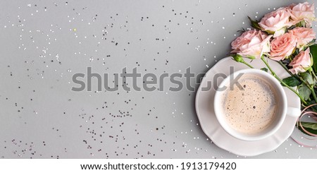Cup of coffee with pink roses on a festive gray background. flat lay. View from above. Copy space.