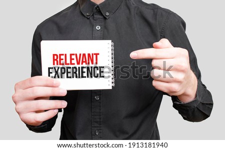 Businessman holding a white notepad with text RELEVANT EXPERIENCE,business concept