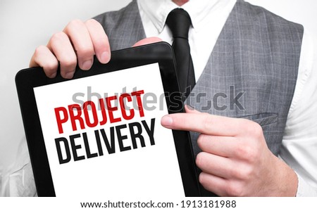Businessman showing business concept on tablet standing in office PROJECT DELIVERY