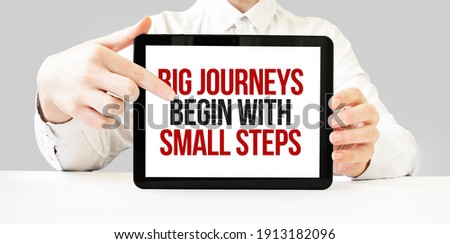 Text Big journeys begin with small steps on tablet display in businessman hands on the white bakcground. Business concept