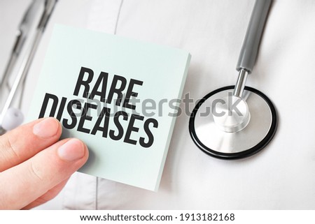 Doctor holding card in hands and pointing the word RARE DISEASES