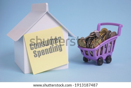 Consumer spending concept. House replica with yellow stick note pad written with retirement plan together and toy cart loaded with coin.                              