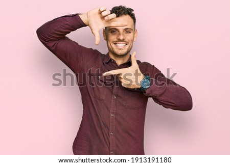 Young hispanic man wearing casual clothes smiling making frame with hands and fingers with happy face. creativity and photography concept. 