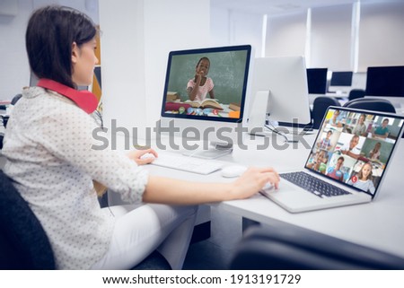 Caucasian female teacher using computer and laptop on video call with school children. Online education staying at home in self isolation during quarantine lockdown.