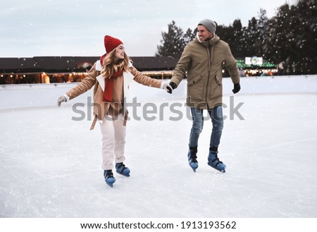 Happy couple skating at outdoor ice rink Royalty-Free Stock Photo #1913193562