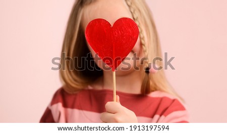Little girl child holding red heart shape candy, share love. Valentine's day concept. 