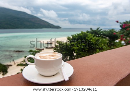 White coffee cup on the balcony in the morning with sunshine and sea view background. Hot coffee for refreshment in the morning. Coffee time in the concept.
