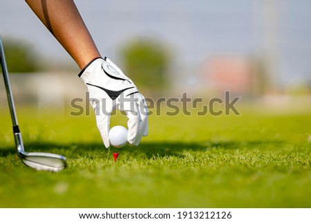 person wearing glove placing golf ball 