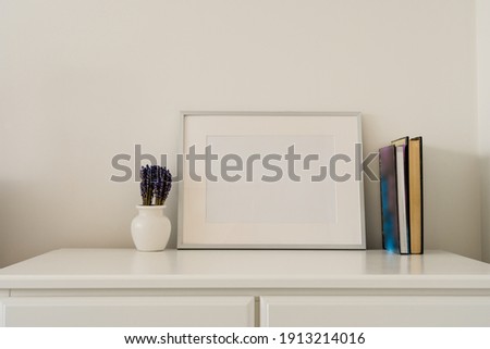 Still life Mock up of silver Picture frame with vase containing flowers and books