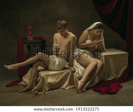Chatting, posting. Modern remake of classical artwork with modern tech theme - young medieval couple on dark background, golden colored. Concept of technologies, devices, communication, ad.