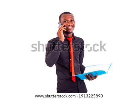 portrait of a young businessman holding a photo album and talking on a mobile phone while smiling.