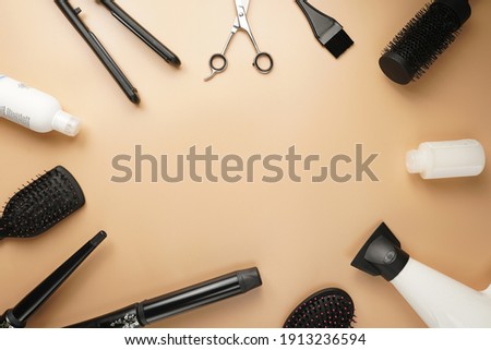 Hair brushes, scissors, hair dryer and curling wands: tools for hairdresser on pastel yellow background arranged as a frame, a template        