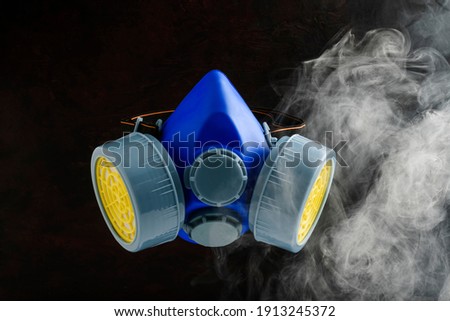 Blue gas mask on black background with smoke or poison gas