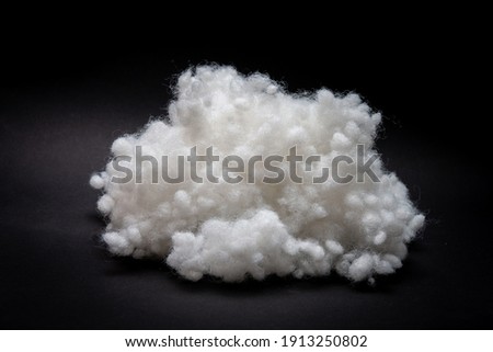 Synthetic fiber, polyester fiber, siliconized holofiber, white sintepon on a black background. It is used as a filler for blankets, pillows, clothes and upholstered furniture. Royalty-Free Stock Photo #1913250802