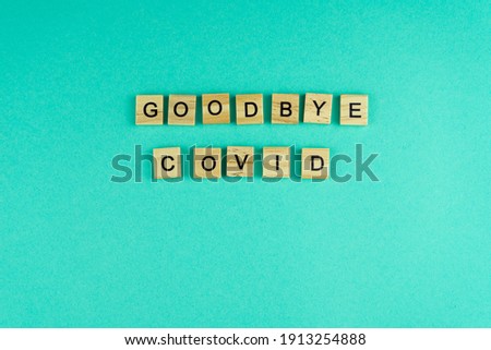 Word goodbye covid. The phrase is laid out in wooden letters. Top view. Motivation. Blue background. Copy space.