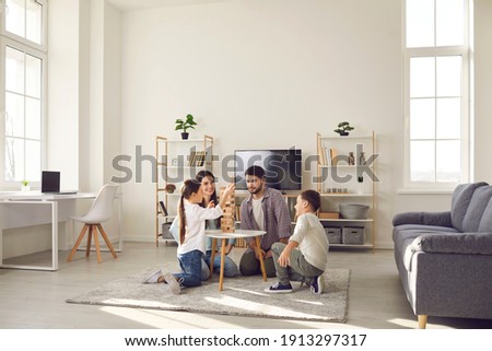 Happy family father mother and two children sitting on floor and playing at home together during weekend. Family spending happy time at home and having fun with children concept Royalty-Free Stock Photo #1913297317