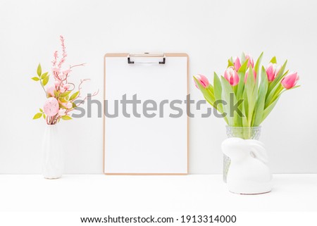 Home interior with easter decor. Mockup with a clipboard and pink tulips in a vase on a light background