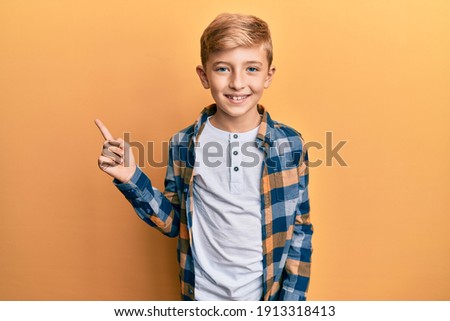 Little caucasian boy kid wearing casual clothes smiling happy pointing with hand and finger to the side 