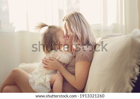 Mother and  daughter toddler playing, kissing, hugging  and smiling, enjoy at the sofa, spending time at home. Moments of tenderness . Happy loving family. Good time at home. Family single mother