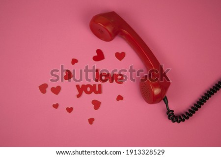 Old telephone handset and red heart on pink paper background. Valentine day.