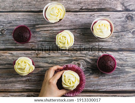 Hands taking rose form muffins on wooden background from zenith view.