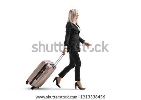 Full length profile shot of a young businesswoman walking and pulling a suitcase isolated on white background Royalty-Free Stock Photo #1913338456