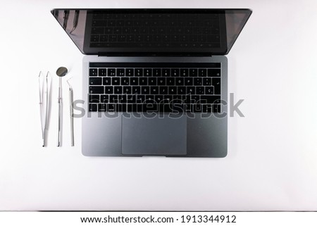 Top view of a gray laptop and a dentist's tools