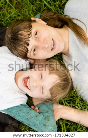 Mother and daughter lie on the grass