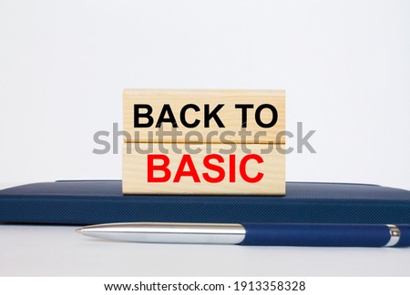 The text Back To Basic on a wooden blocks, lying on a Notepad with a metal blue pen. Business concept photo