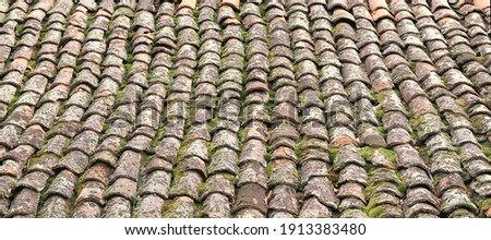 Old roof tiles. House roof with old weathered dirty red tiles. Vintage tiles as background. High resolution background. Panoramic image, hi-res banner. Royalty-Free Stock Photo #1913383480