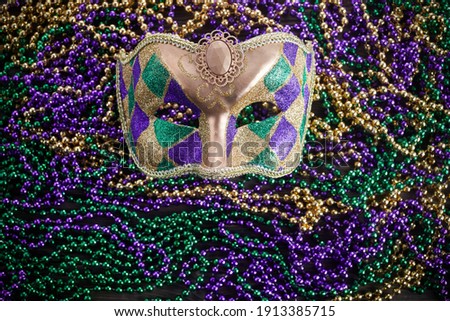 A group of Venetian and New Orlean Mardi gras mask with colorful beads on dark background