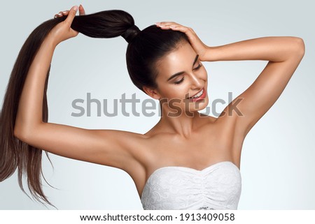 Caucasian beautiful girl holds hair in hand, raise up hands. Beauty young woman, salon body and armpit skin care, smooth armpit skin, hair removal and sugaring. Happy girl with closed eyes Royalty-Free Stock Photo #1913409058